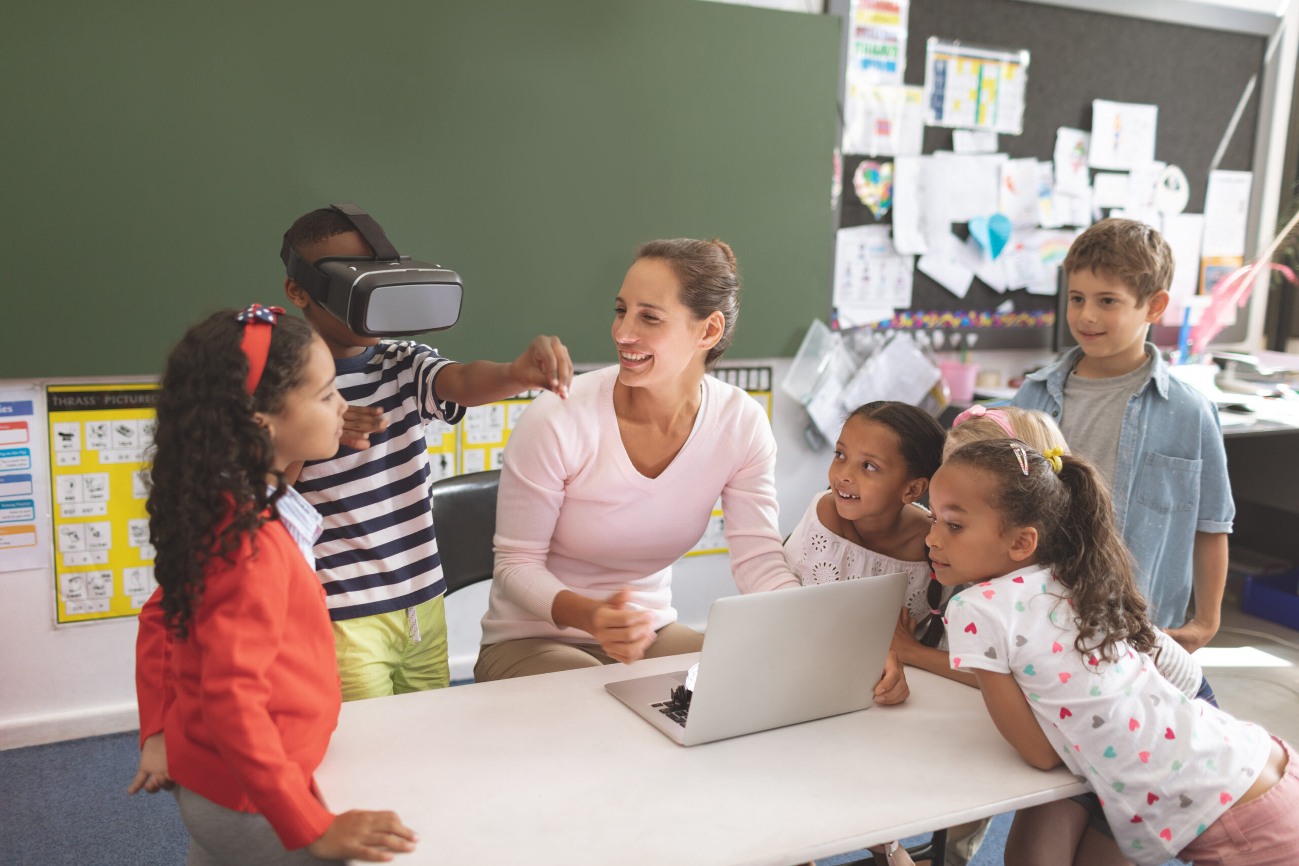 Schoolboy using virtual reality headset at school in classroom with his classmates and teacher.