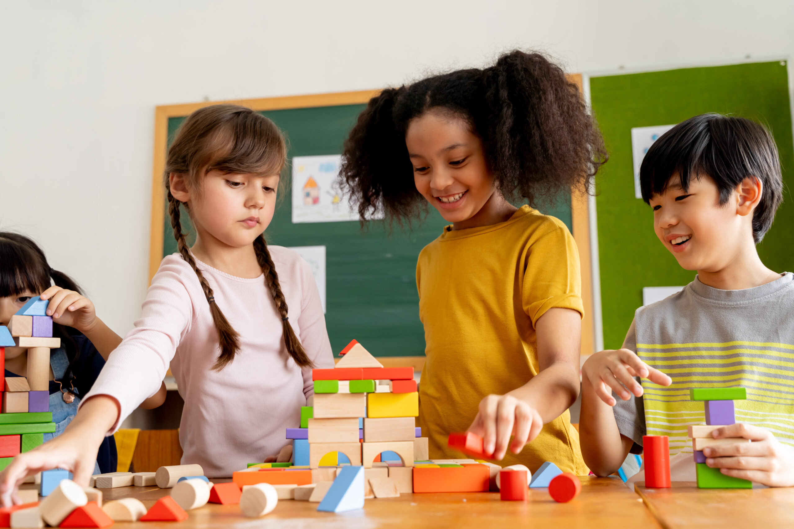 Group of school friends using toy blocks in classroom.